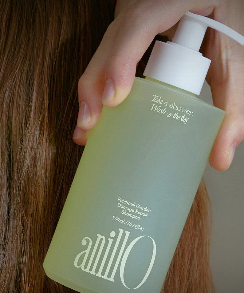 ANILLO Patchouli Garden Damage Repair Shampoo 300ml bottle held near hair for damage repair and nourishment.