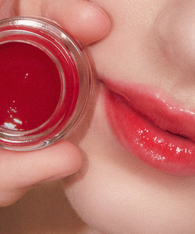 Close-up of lips and ANILLO Petal Glow Balm, showcasing vibrant color and smooth texture.