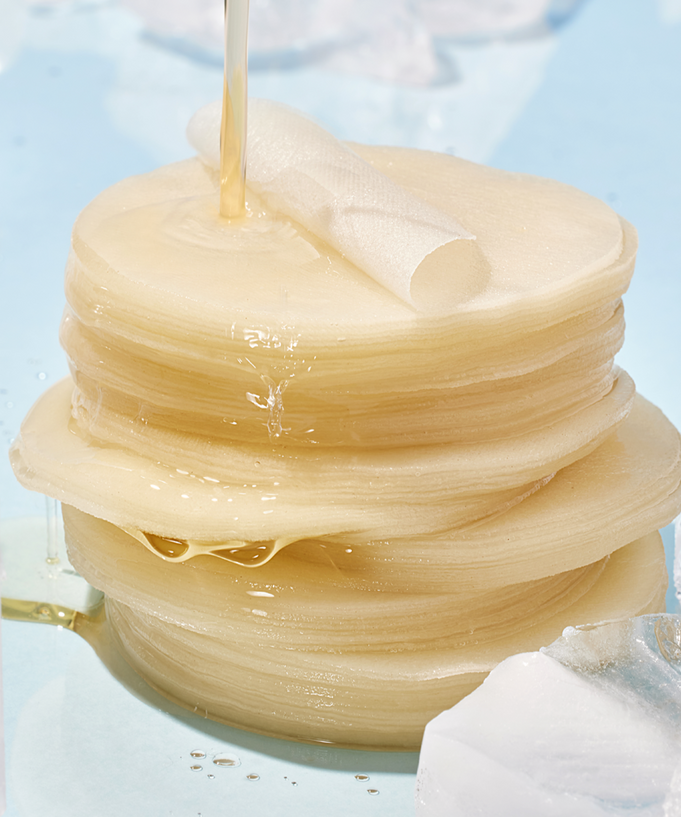 ANUA 8 Hyaluronic Acid Catechin Calming Pads 110 Pads on a light blue surface with clear liquid pouring over them.