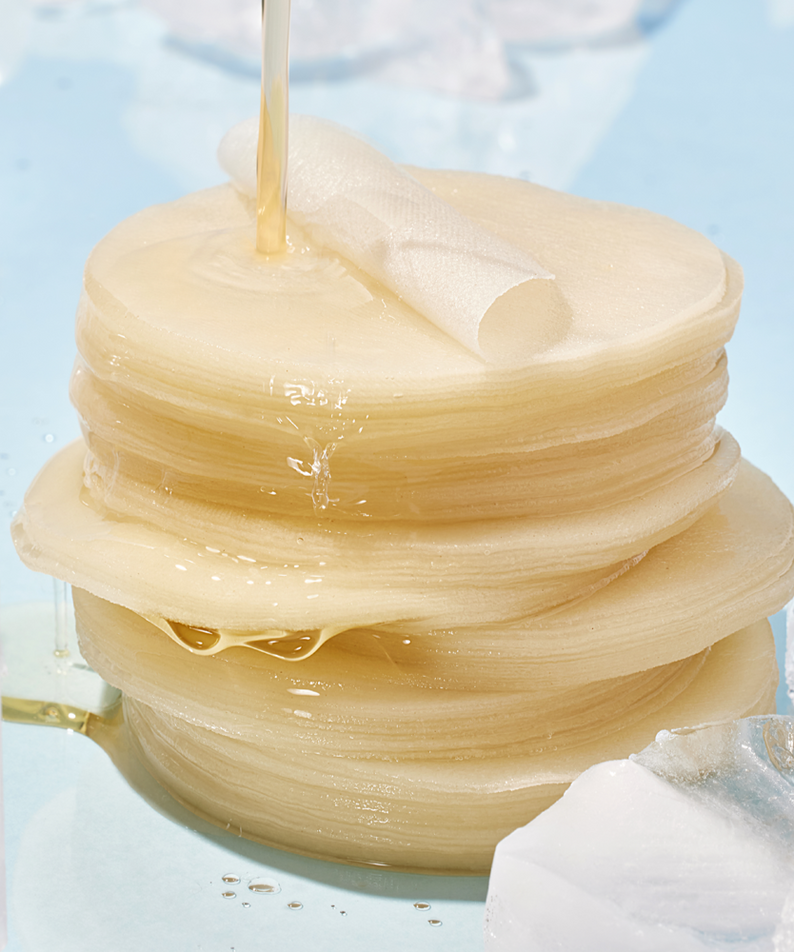 ANUA 8 Hyaluronic Acid Catechin Calming Pads 110 Pads on a light blue surface with clear liquid pouring over them.