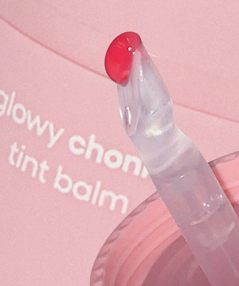 Close-up of AOU Glowy Chonky Tint Balm applicator with a tint of pink balm visible on a pink background.