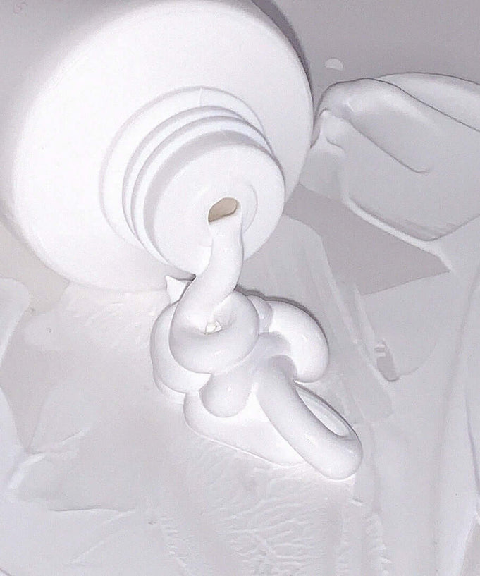 AOU Tone-Up Dazzling Cream spread out from an open tube, showcasing its texture and smoothing properties.