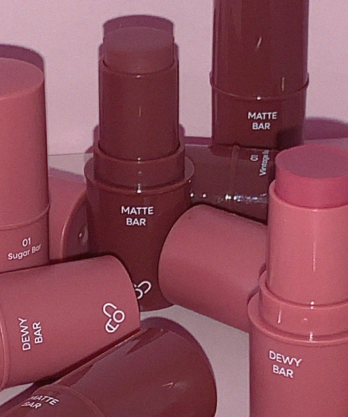 Assorted AOU Matte Bar and Dewy Bar lipsticks displayed on a reflective surface.