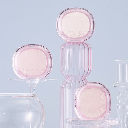 A'PIEU Juicy Pang Glimmering Highlighter displayed on elegant glassware with soft lighting background.