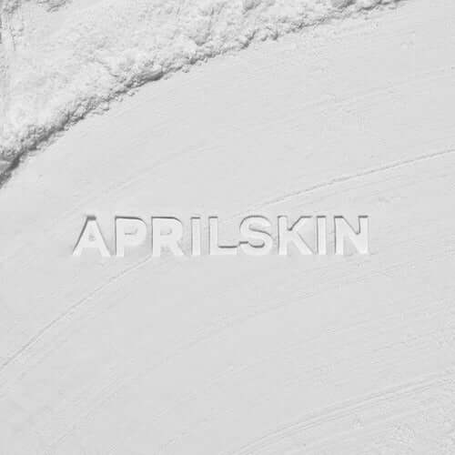 APRILSKIN Blur Skin Powder texture detail with branded imprint on soft white background. Ideal for smoothing skin appearance.