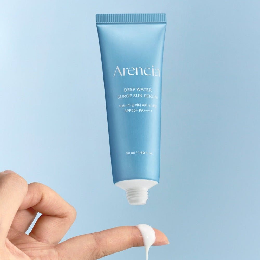 Hand applying ARENCIA Deep Water Surge Sun Serum 50ml with a blue tube and SPF protection.
