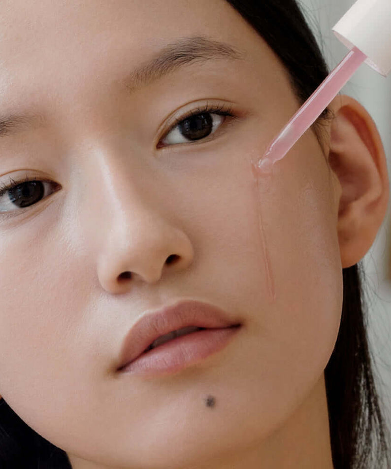 Woman applying ARENCIA Red Smoothie Serum 8 30ml to her face, demonstrating skincare application technique.