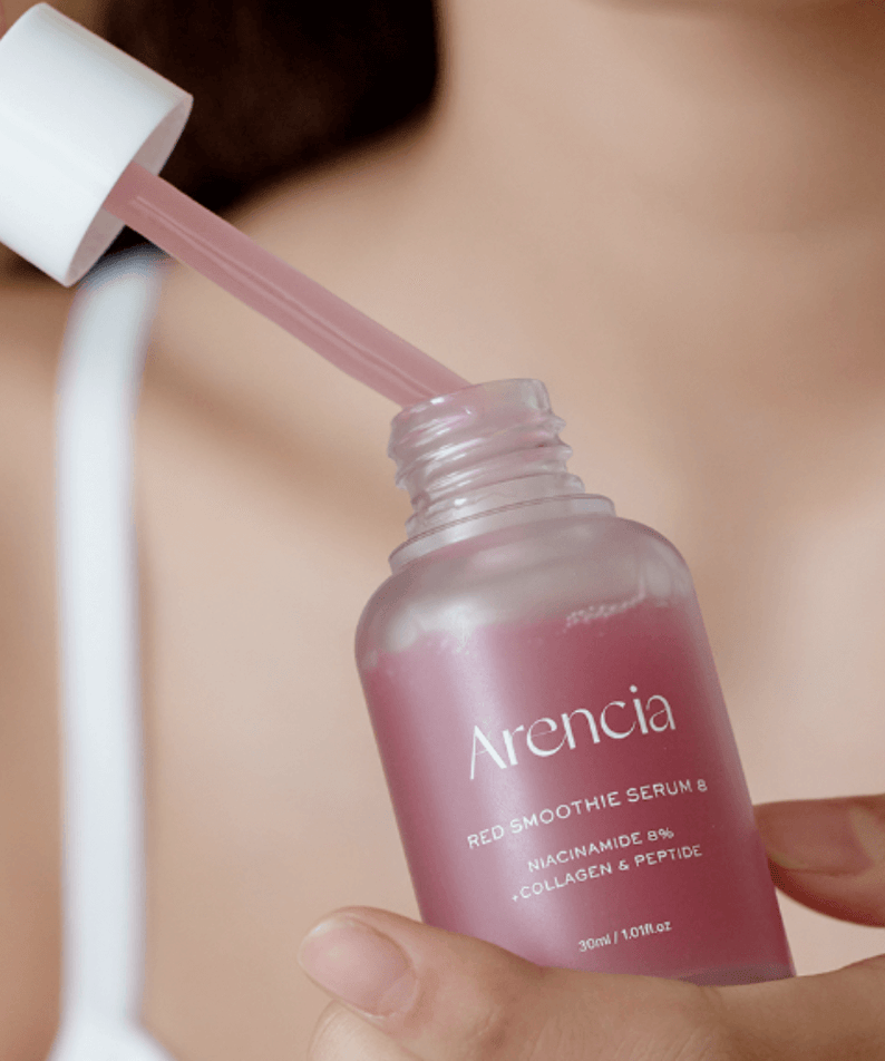 Person applying ARENCIA Red Smoothie Serum 8 30ml from a dropper bottle.