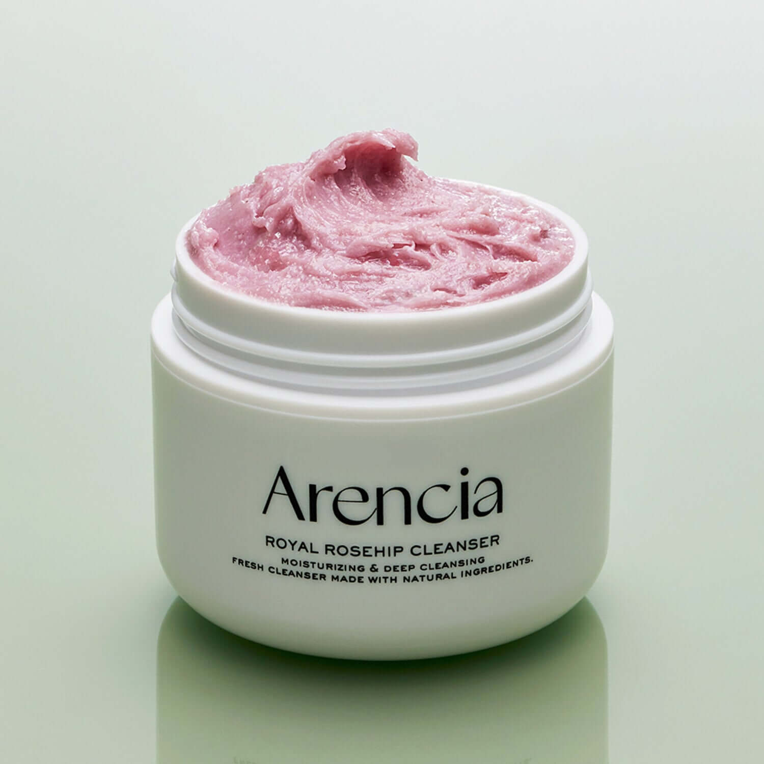 Open jar of ARENCIA Royal Rosehip Fresh Cleanser Rice Soap 120g with pink cream on a green background.