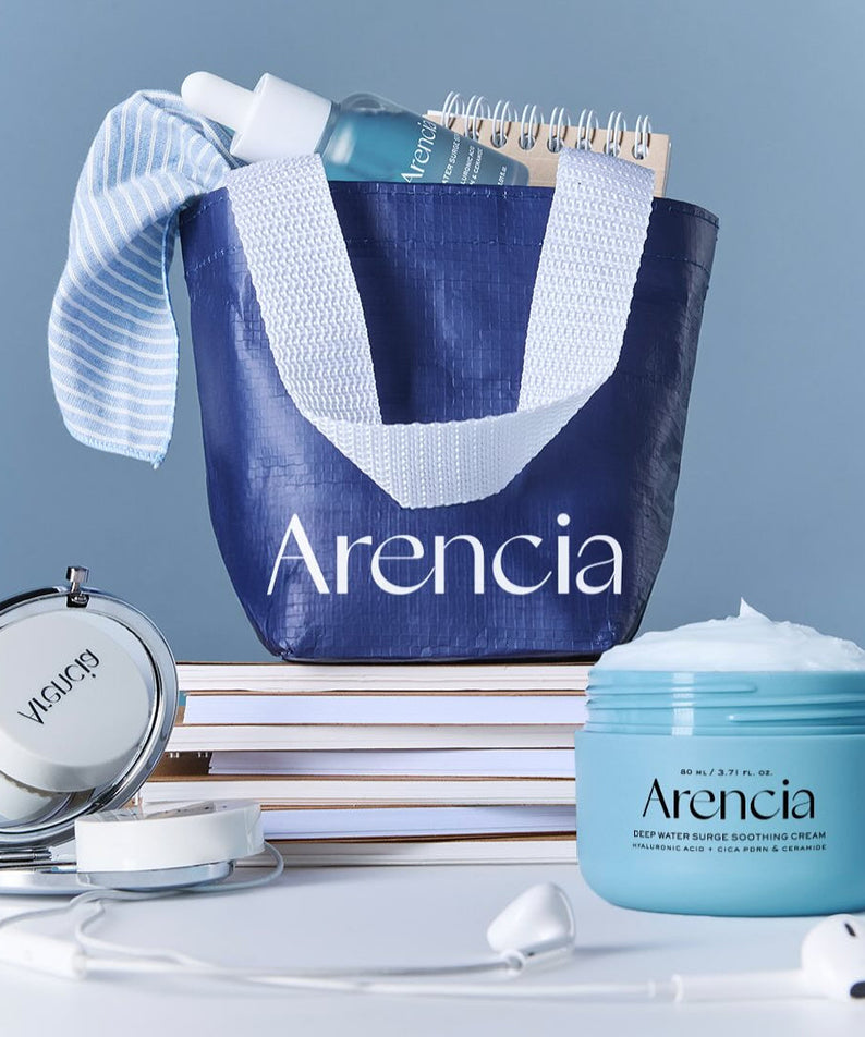 ARENCIA Deep Water Surge Soothing Cream 80ml jar beside a blue tote with skincare products and a notebook on a table.
