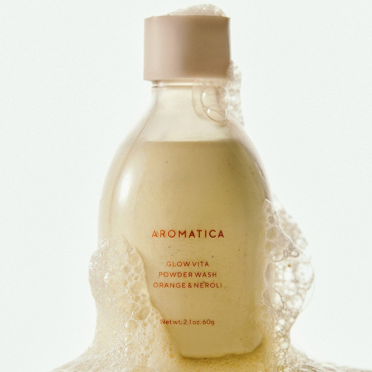 AROMATICA Glow Vita Powder Wash Orange & Neroli 60G with foaming bubbles in a bottle.