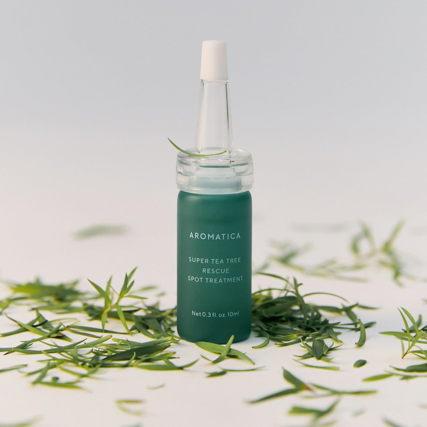 AROMATICA Super Tea Tree Rescue Spot Treatment 10ML product bottle surrounded by tea tree leaves