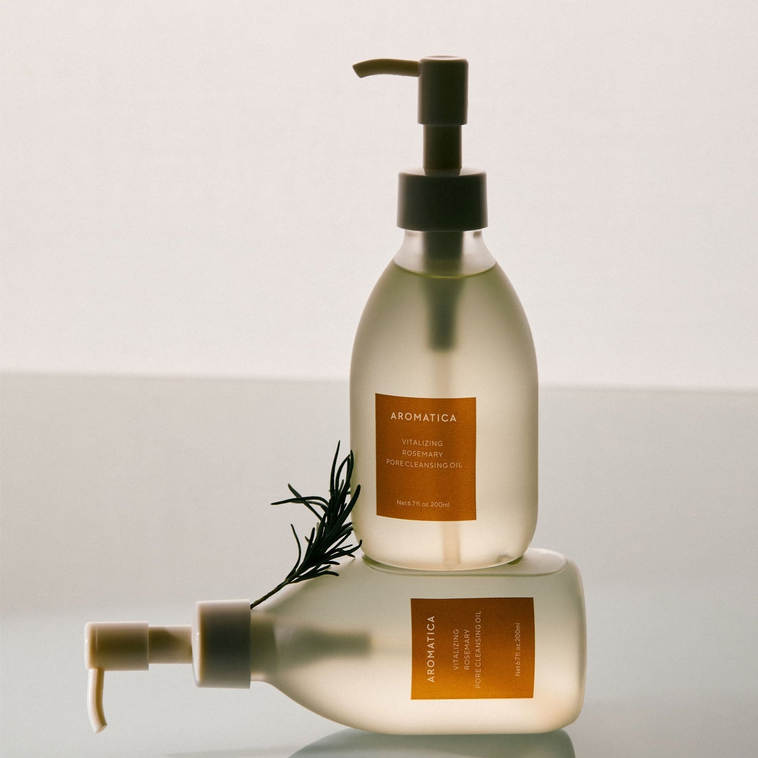 AROMATICA Vitalizing Rosemary Pore Cleansing Oil 200ML bottles on a reflective surface with rosemary sprig.