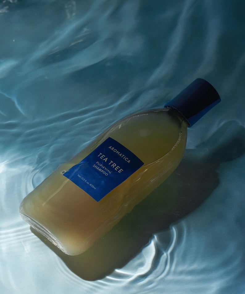 AROMATICA Tea Tree Purifying Shampoo 750ML bottle in calming water setting, promoting a refreshing and cleansing hair care experience