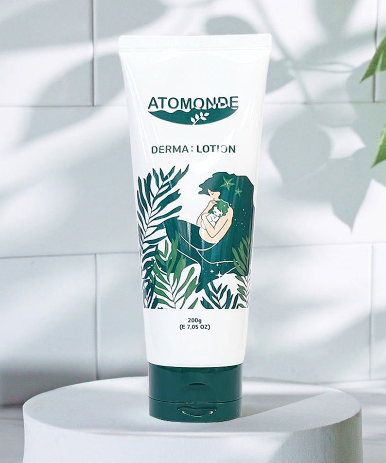 ATOMANDE Baby Derma Infant Lotion 200g bottle on a white surface with green leaf design in a bright setting.