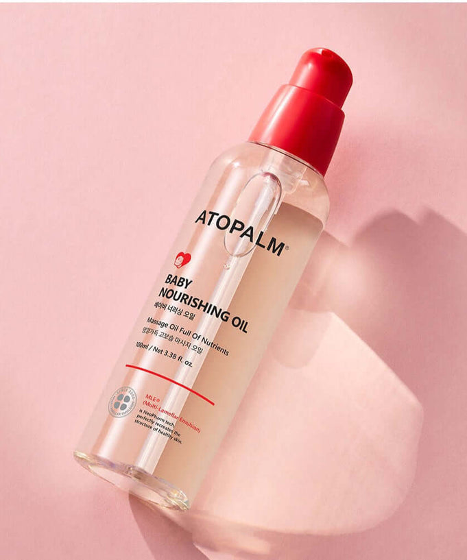 ATOPALM Baby Nourishing Oil 100ml bottle on pink background, skincare product for infants, hydrating and soothing oil for baby care.