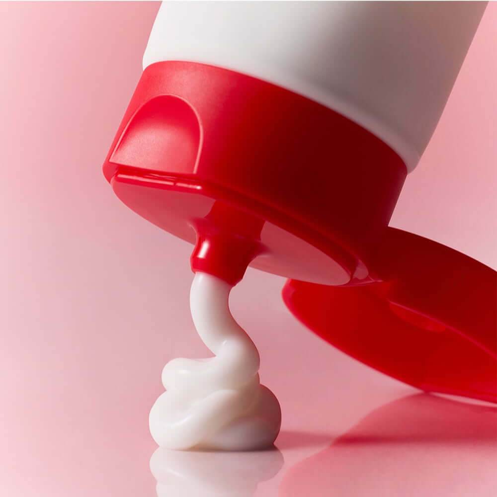 ATOPALM Face Lotion 80ml tube dispensing cream on a pink background