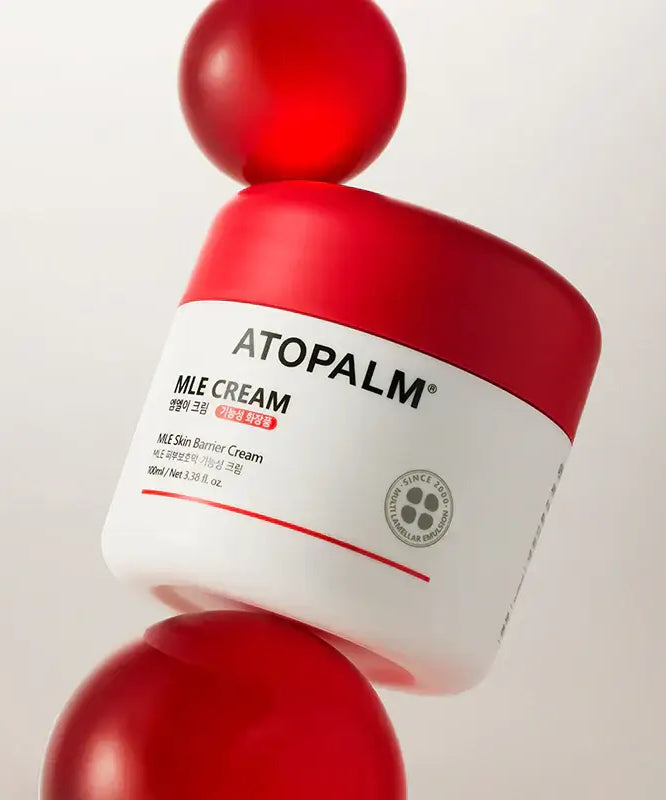 ATOPALM MLE Cream 160ml (Single Type) jar on red spheres, showcasing skincare product packaging.