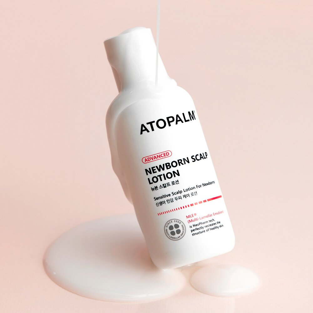 ATOPALM Newborn Scalp Lotion 100g bottle with lotion dripping on pink background