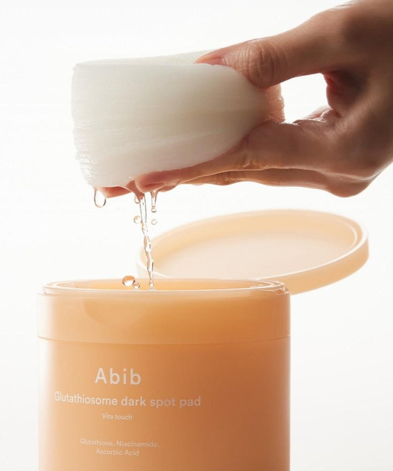 ABIB Glutathiosome Dark Spot Pad Vita Touch 60 EA, showing hand holding a pad above container, with product details visible.