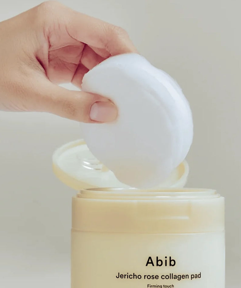 ABIB Jericho Rose Collagen Pad Firming Touch 60 Pads being lifted from the container, showcasing skincare product.