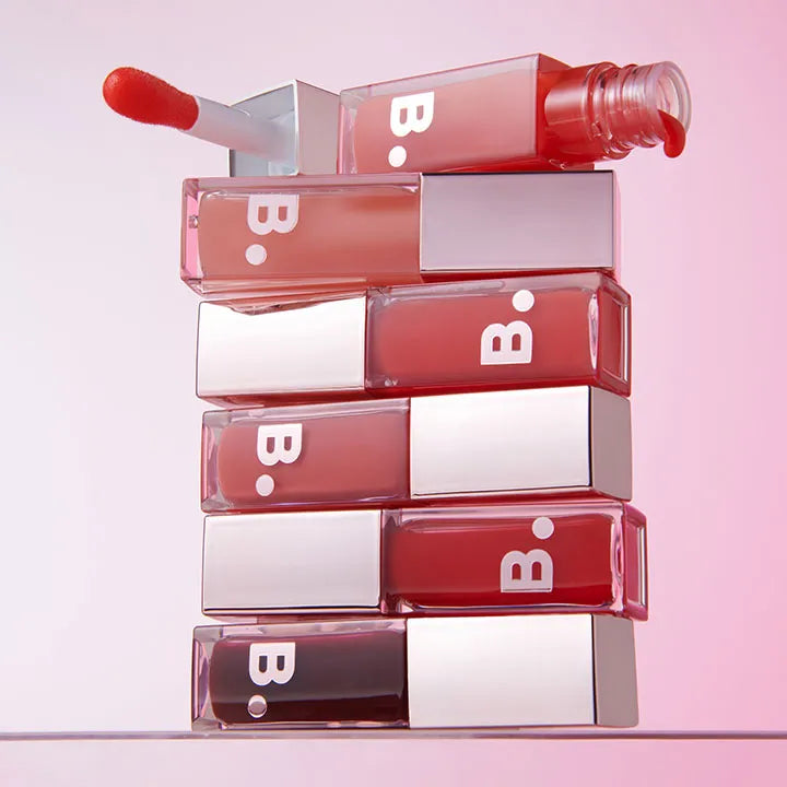 Stack of BANILA CO Hydrating Lip Oil bottles with applicator displayed