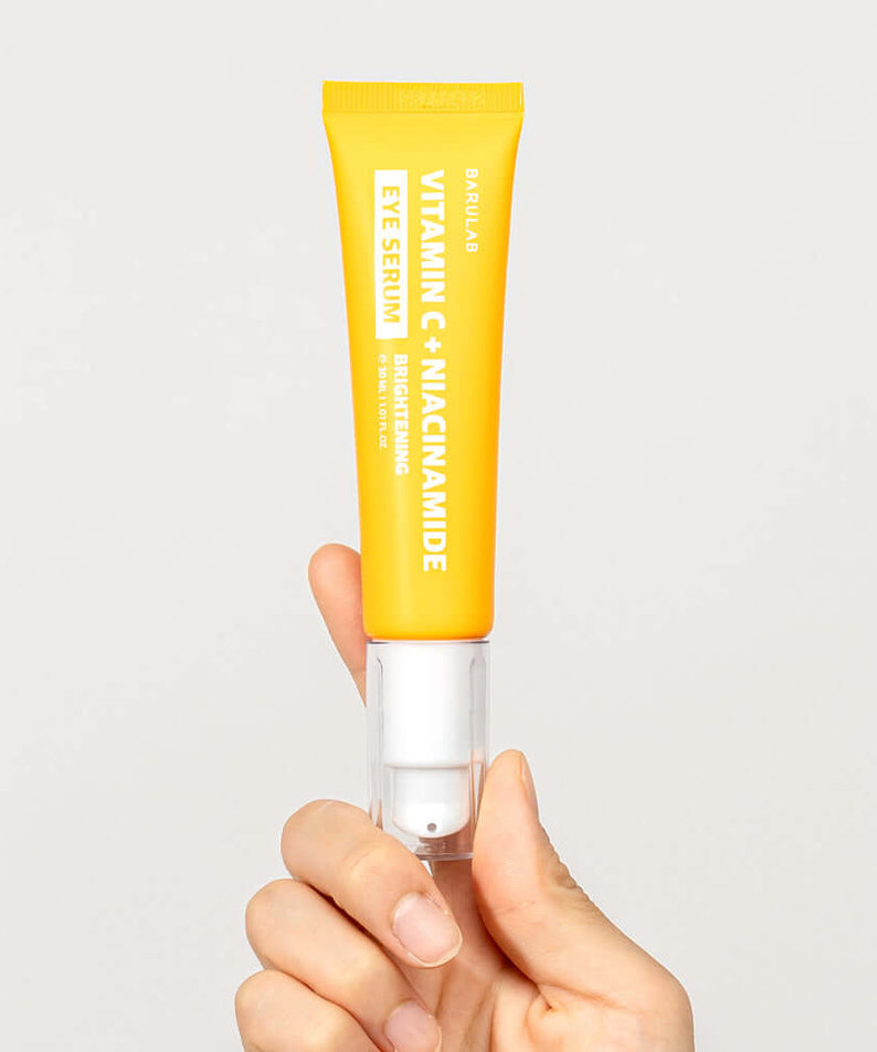 Hand holding BARULAB Vitamin C Niacinamide Whitening Eye Serum 30ml in bright yellow packaging