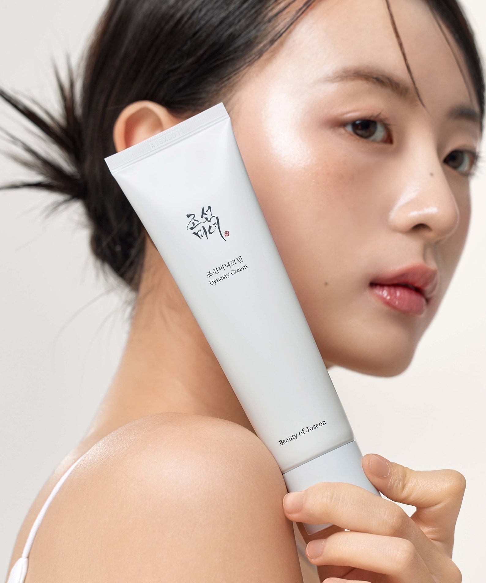 Woman holding BEAUTY OF JOSEON Dynasty Cream 100ml next to her face
