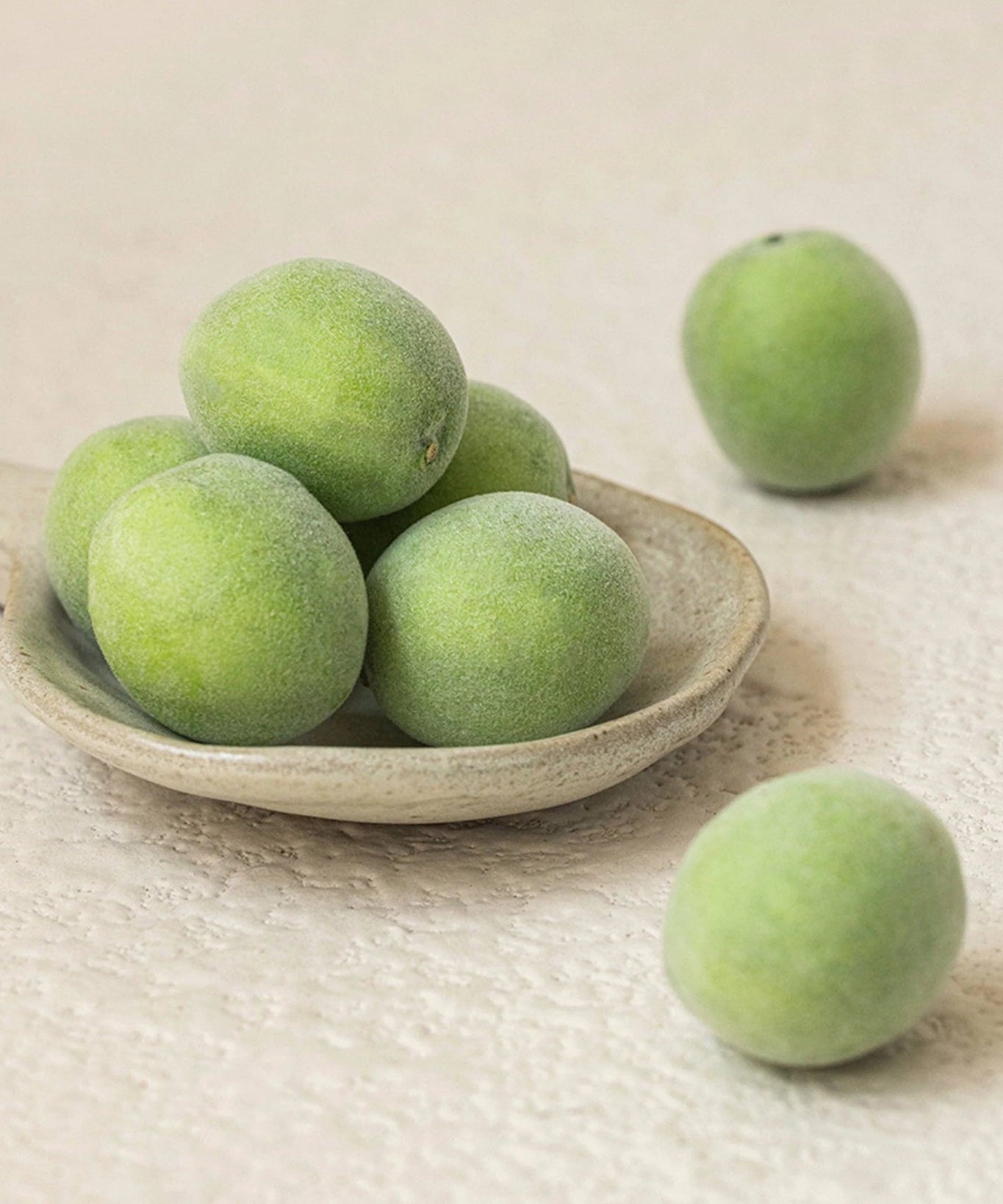 Fresh green plums on a wooden spoon, featured in BEAUTY OF JOSEON Green Plum Refreshing Toner AHA + BHA 150ml.