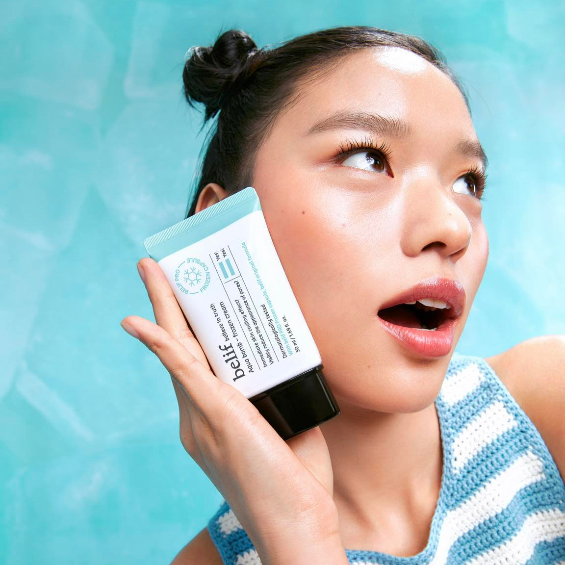 Person holding BELIF Aqua Bomb Frozen Cream 50ml against a blue background.