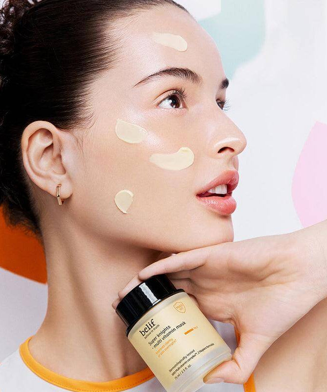 Woman applying BELIF Super Knights Multi Vitamin Mask 75ml on face for nourishment and skincare, holding product jar.