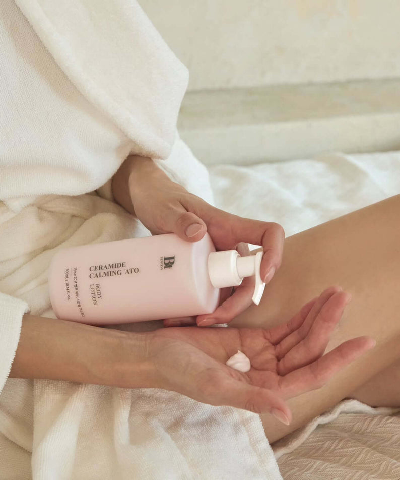 Person applying BENTON Ceramide Calming Ato Body Lotion 300ml, ideal for soothing and hydrating skin, in a serene setting.