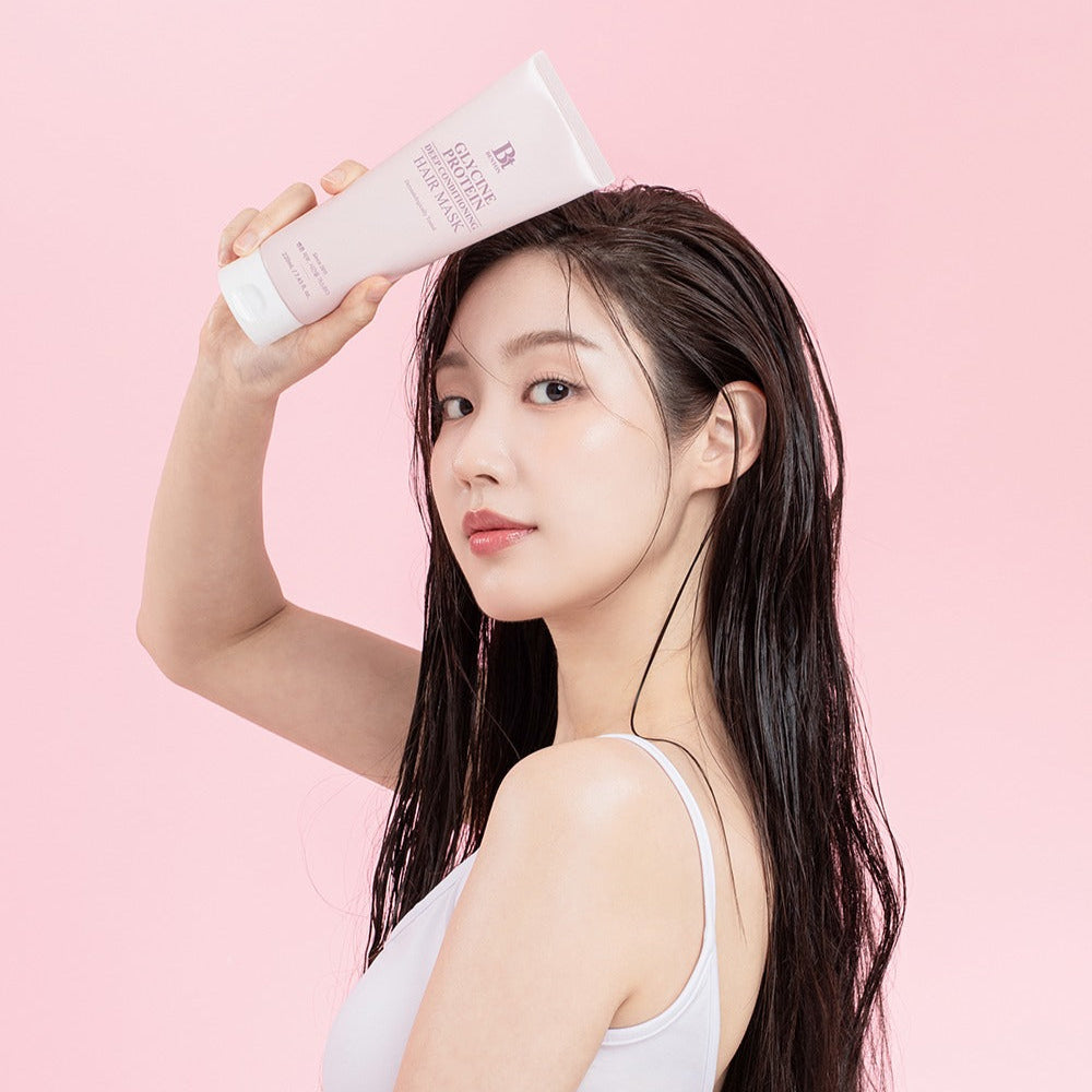 Woman holding BENTON Glycine Protein Deep Conditioning Hair Mask 220ml against pink background