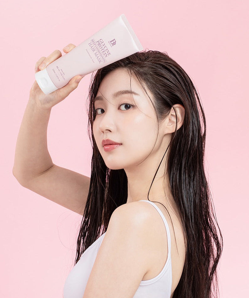 Woman holding BENTON Glycine Protein Deep Conditioning Hair Mask 220ml against pink background