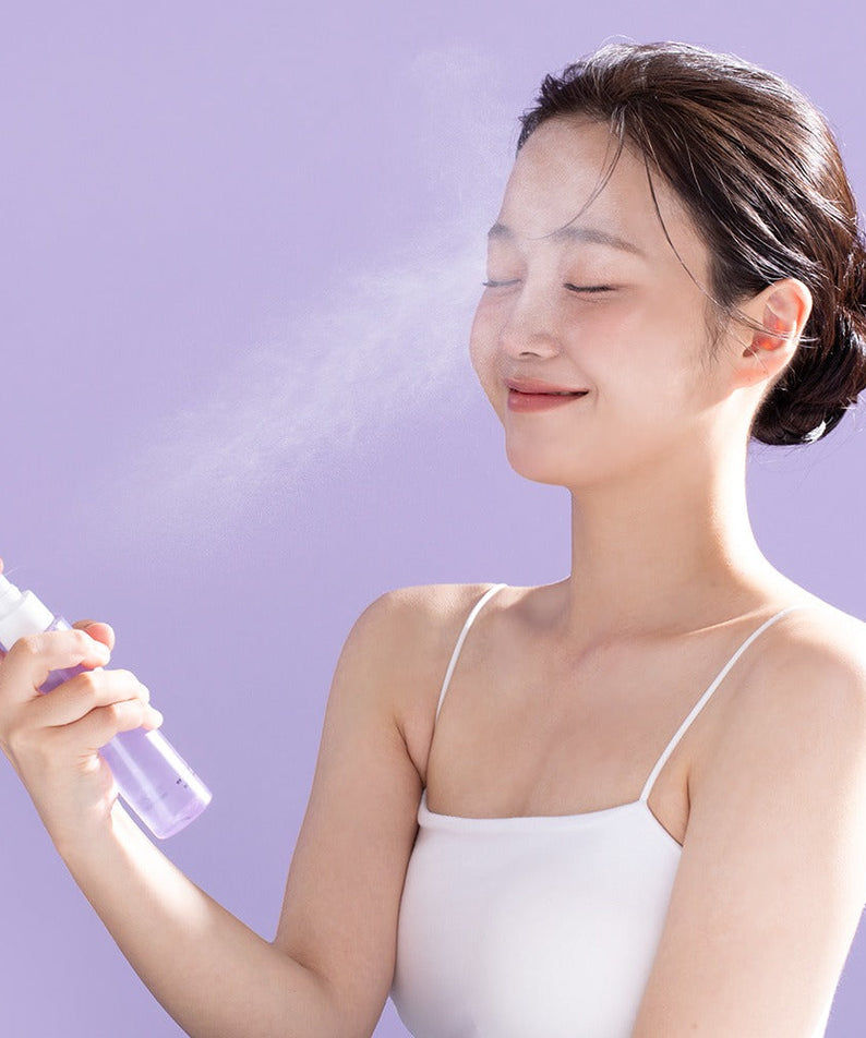 Woman using BENTON Guava Hydrating Collagen Mist 100ml on her face against a purple background.