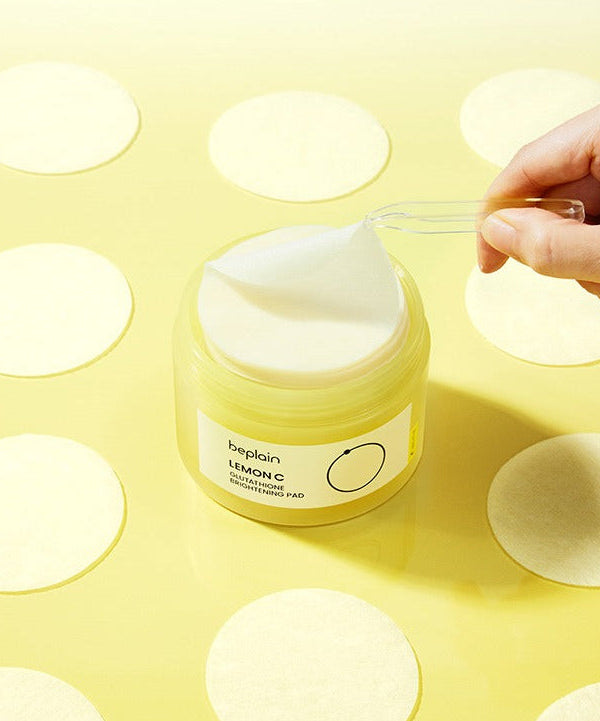 BEPLAIN Lemon Seed Glutathione Whitenning Pads 70 Sheets in a jar with a hand lifting one pad on a yellow background