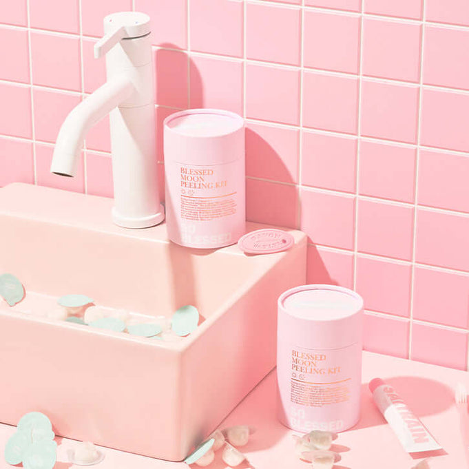 BLESSED MOON Pelling Kit displayed on a pink bathroom counter with white faucet and petals