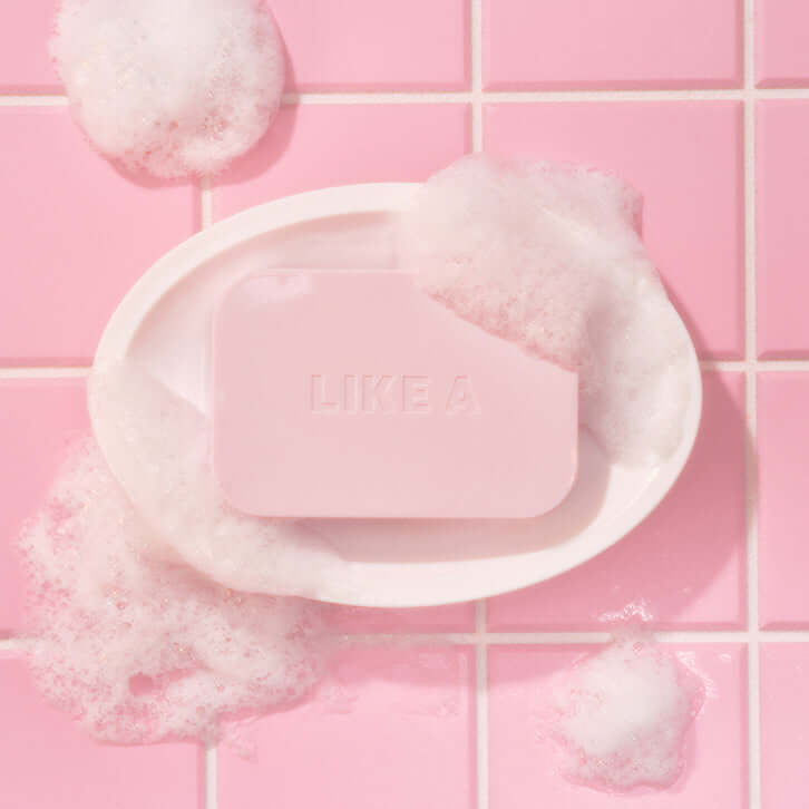 Bubbly pink soap bar in white dish on pink tiled background, part of BLESSED MOON Soap Palette.