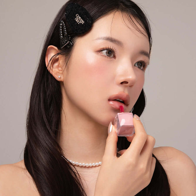 Woman applying BLESSED MOON Veil Glow Lip Tint, showcasing a subtle pink lip color and radiant glow effect on lips.