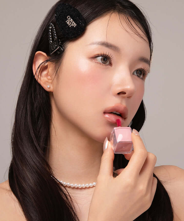 Woman applying BLESSED MOON Veil Glow Lip Tint, showcasing a subtle pink lip color and radiant glow effect on lips.