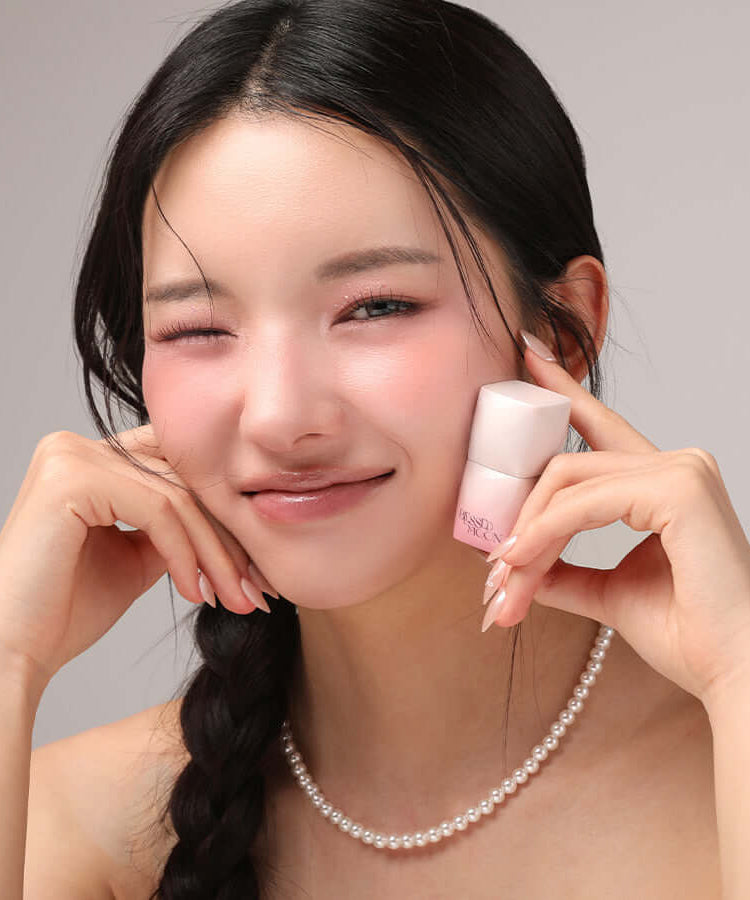 Smiling woman holding BLESSED MOON Veil Melting Color Blush next to her face, showcasing the product's effect on cheeks.