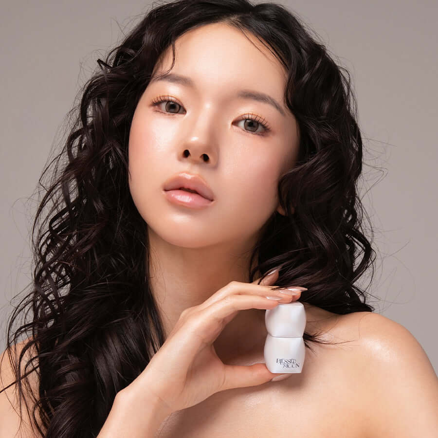 Model holding BLESSED MOON Veil Melting Glass Highlighter showcasing radiant skin