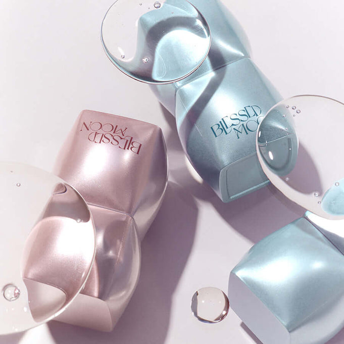 BLESSED MOON Veil Mood Lip Gloss bottles with reflective water droplets on a smooth surface.