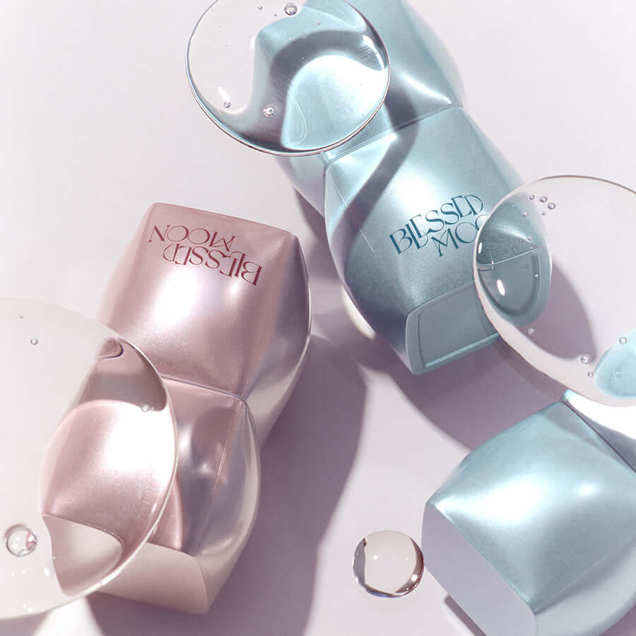 BLESSED MOON Veil Mood Lip Gloss bottles with reflective water droplets on a smooth surface.