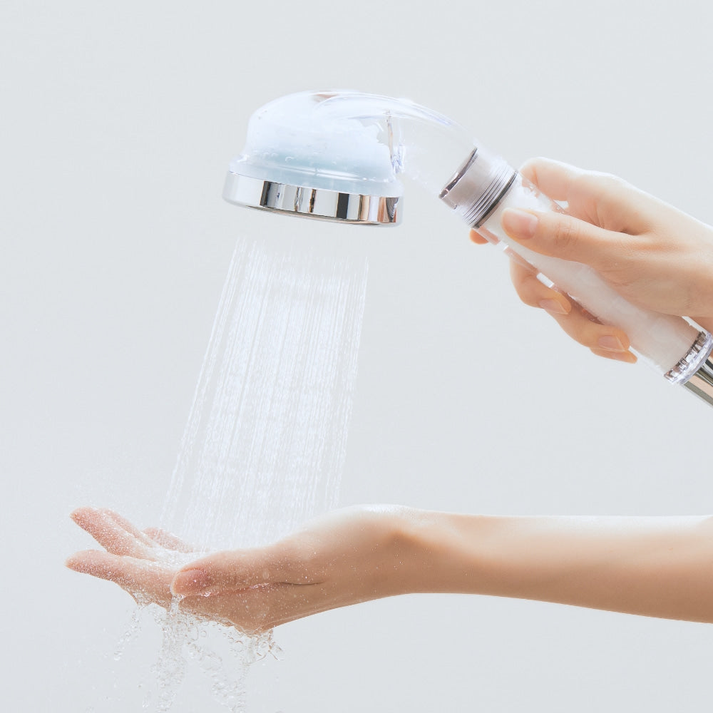 Hands holding BODYLUV Vita Puresome Shower Head with water flowing, showcasing its design and functionality.