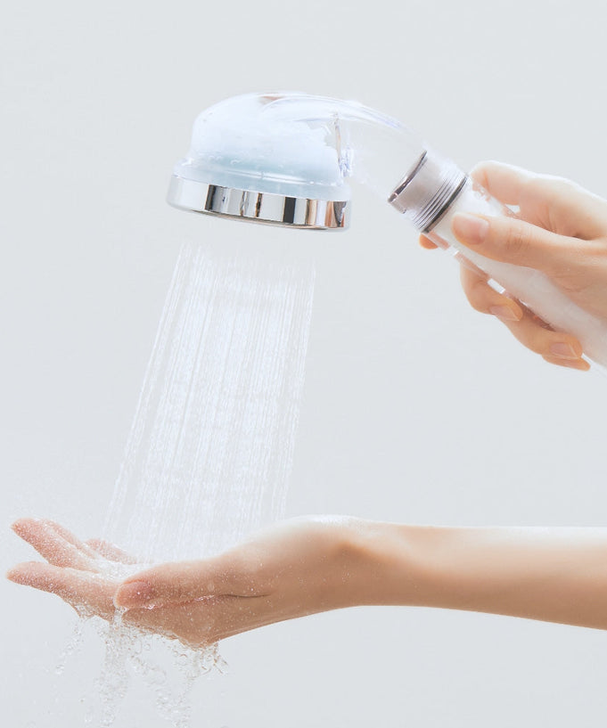 Hands holding BODYLUV Vita Puresome Shower Head with water flowing, showcasing its design and functionality.