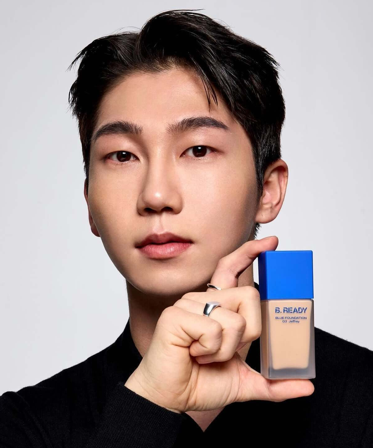 Model holding B.READY Blue Foundation bottle, showcasing the product's sleek design.