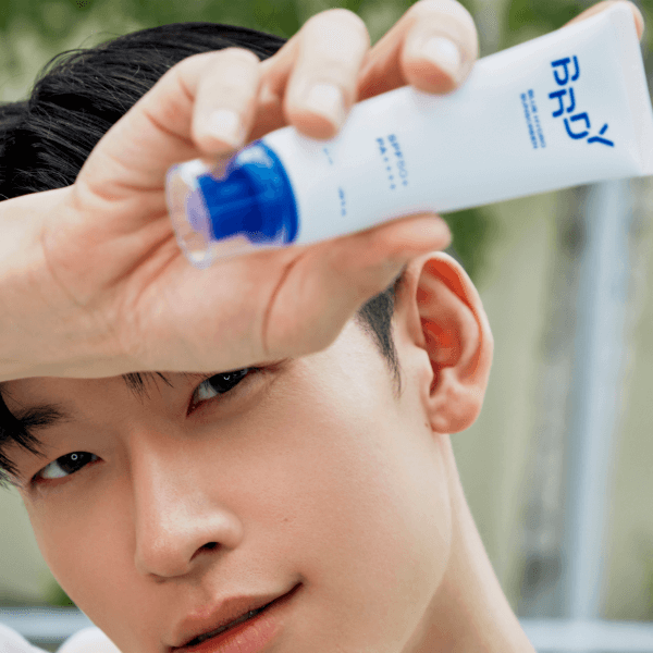 Gentleman Korea model applying B.READY Blue Moisture Sun Cream 50ml for men, blue-capped sunscreen tube held near face