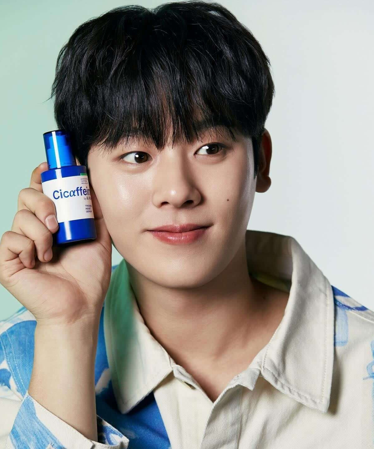 Person holding B.READY Cicaffein trouble Reset Serum 40ml close to face, showcasing skincare product.