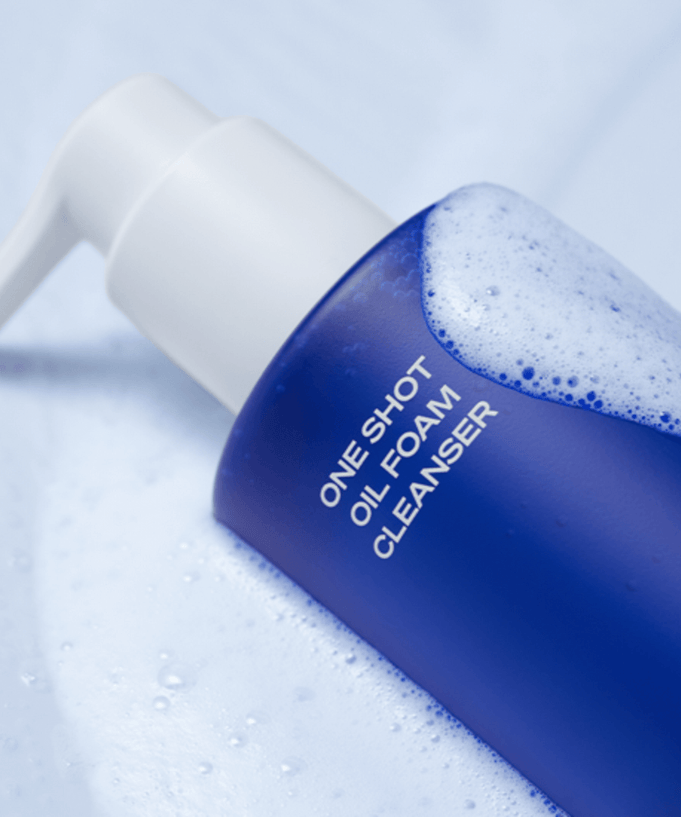 Close-up of B.READY Oil Foam Cleanser 200ml bottle with foamy bubbles on a blue surface.